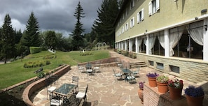 Une terrasse avec des meubles d’extérieur, un sol en pierre et des plantes en pot.
