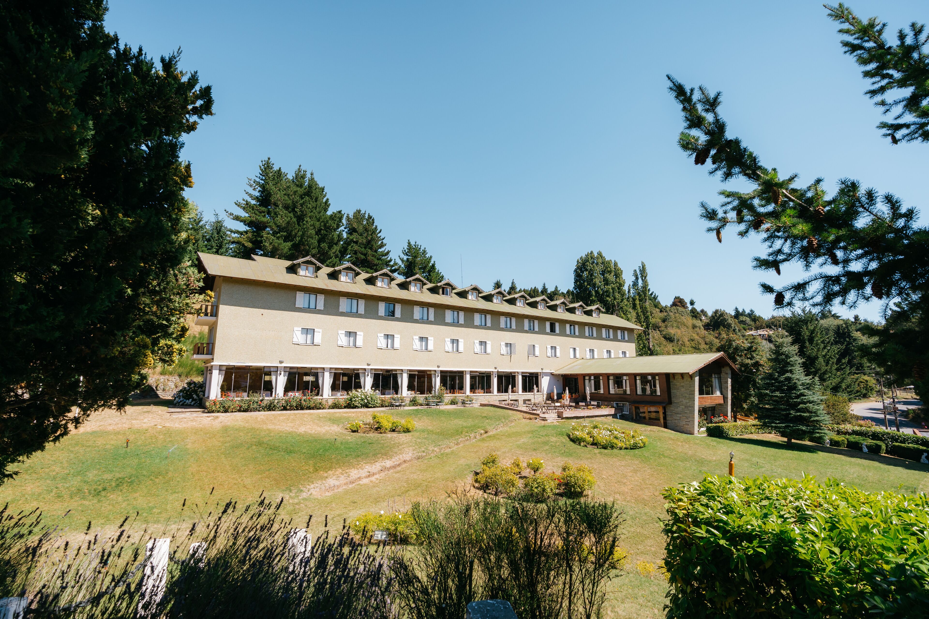 Un gran hotel con varios pisos, un espacio al aire libre cubierto y un césped bien cuidado.