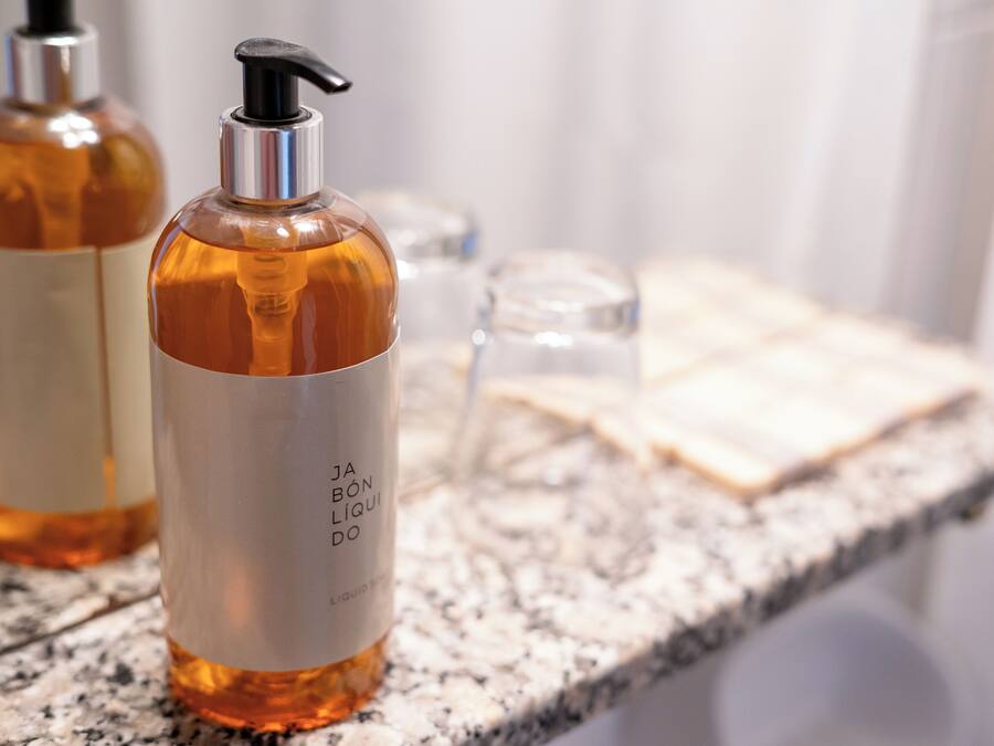 Un comptoir de salle de bain avec un flacon de savon liquide et un verre d’eau.
