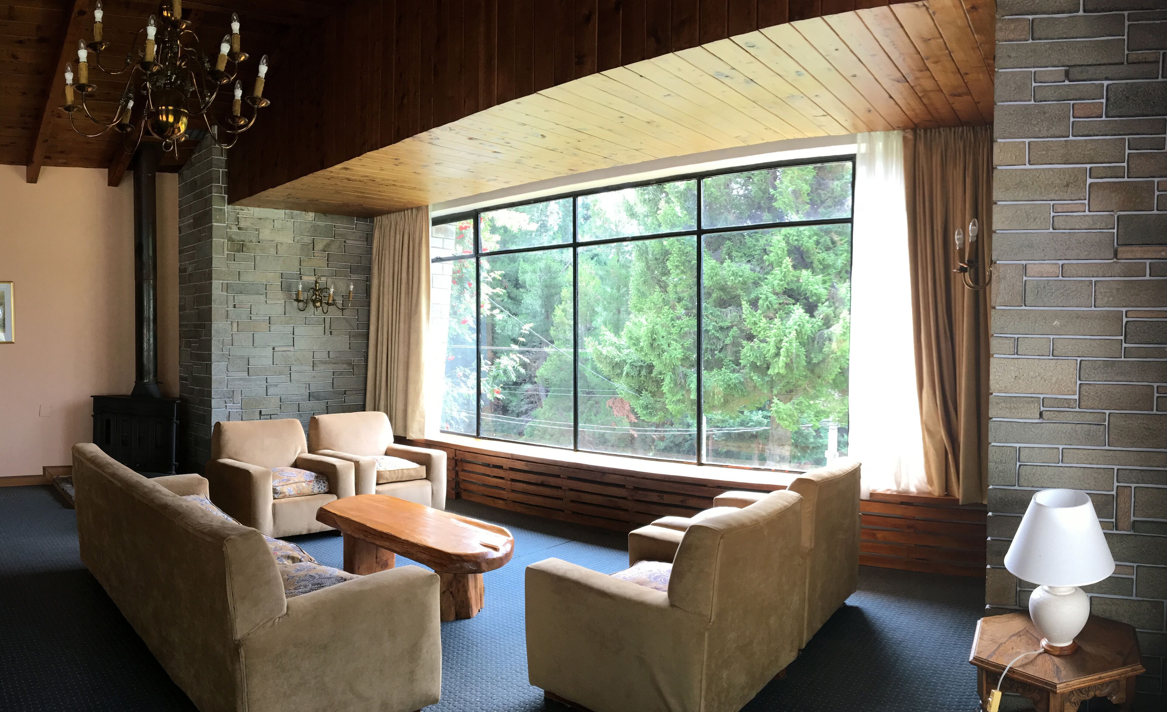 Un salon chaleureux avec une cheminée en pierre, de grandes fenêtres et des sièges confortables.