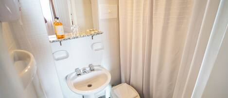 Un baño con lavamanos blanco, inodoro y cortina de ducha.