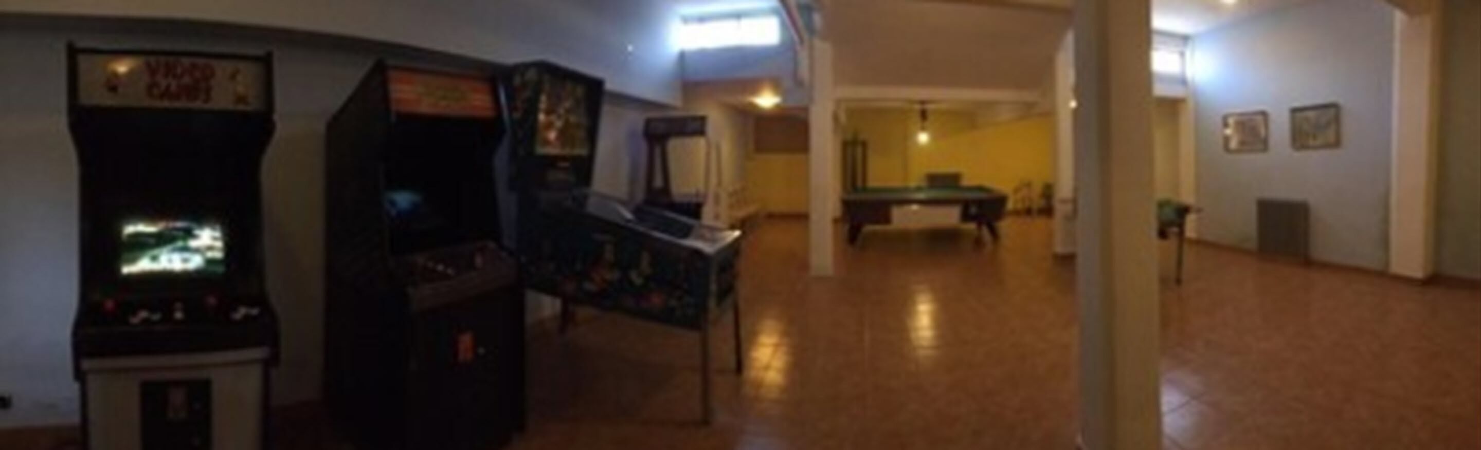 A room with arcade machines, a pool table, and a billiards table.