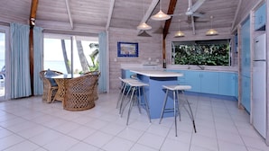 Una cocina con barra, piso de baldosas blancas, techo de madera y armarios azules.