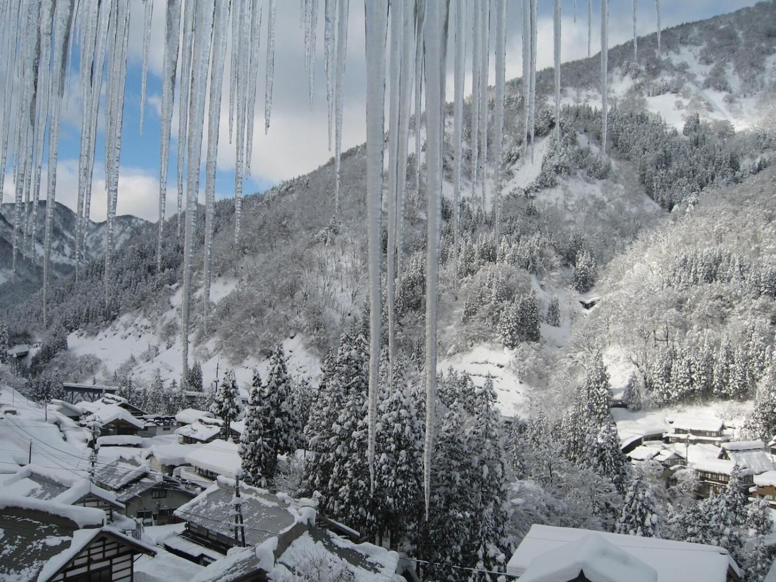 A snowy mountain landscape with buildings and trees covered in snow.
