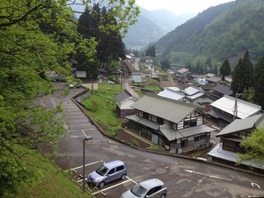 A residential area with traditional Japanese houses, a parking lot, and a mountainous backdrop. - Gokasanso (Nanto)
