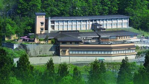 A large building with multiple floors, surrounded by lush green trees. - Gokasanso (Nanto)