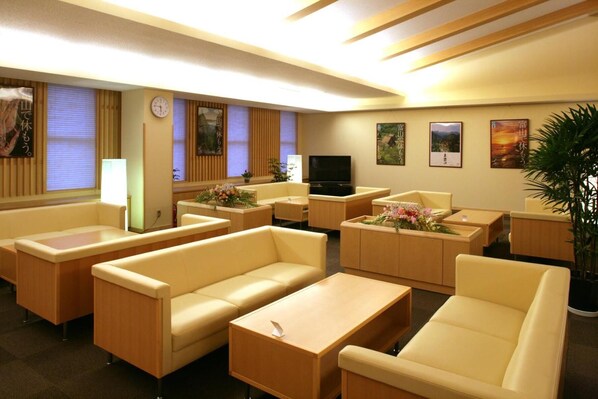 A hotel lobby with sofas, a TV, and artwork on the walls.