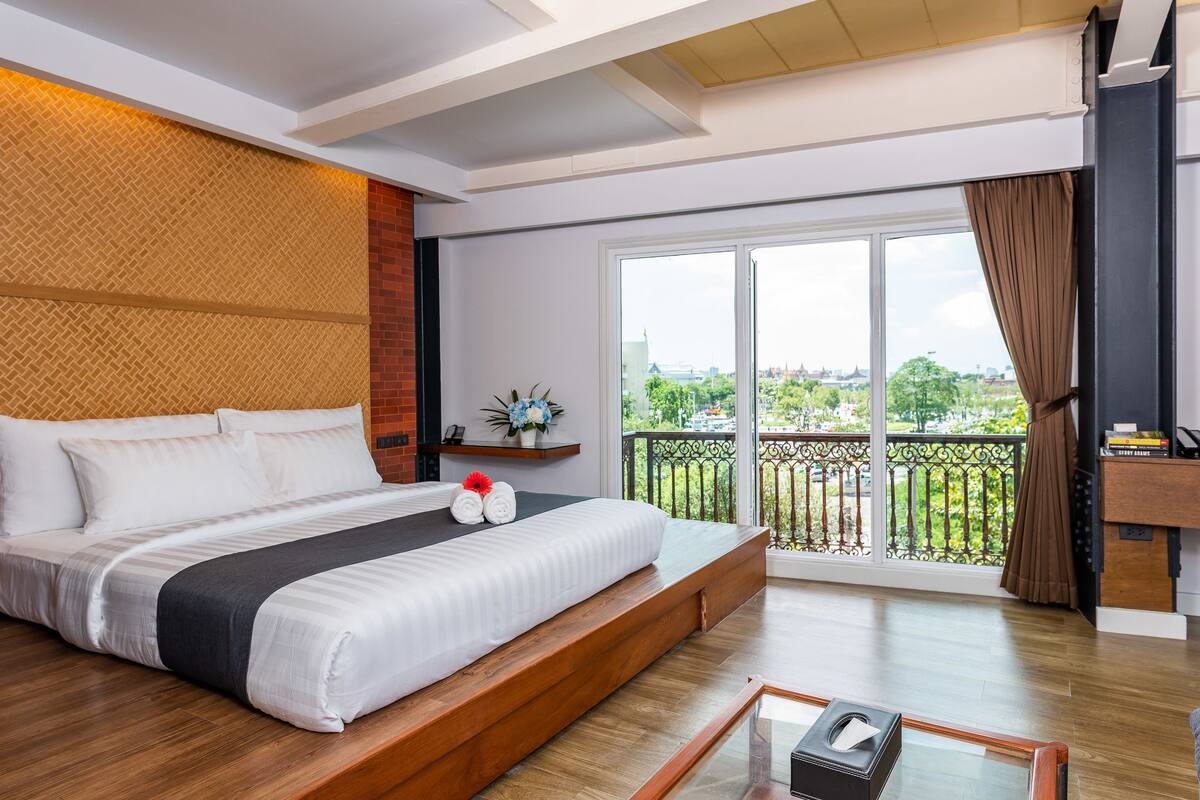 Une chambre d’hôtel moderne dotée d’un grand lit, d’un balcon avec vue et d’un bureau avec un ordinateur.