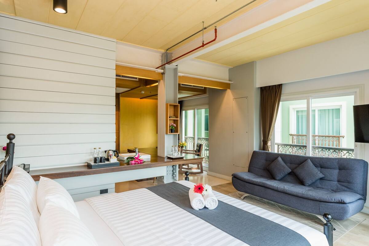 Une chambre d’hôtel comprenant un lit, un canapé, un bureau avec une chaise, une fenêtre avec vue et un balcon.