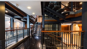 Un intérieur à plusieurs niveaux, doté d’un escalier central, de rampes en métal et d’un plancher poli.