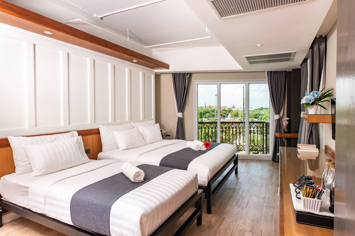 Une chambre d’hôtel avec deux lits, un balcon avec vue et un minibar.