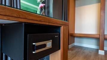 A black safe with a keypad, a wooden counter, and a small vase with flowers on top.