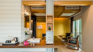 Une chambre d’hôtel moderne avec une table à manger en bois, un lavabo intégré et un coin salon avec des chaises.