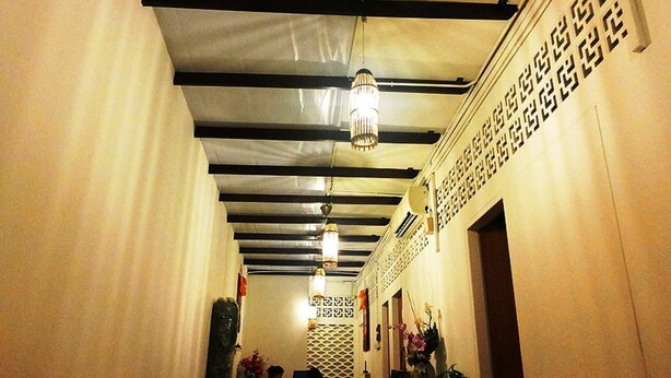Un couloir avec un mur orné de motifs et des luminaires suspendus.