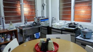 Une cuisine équipée d’un évier, d’une cuisinière et de divers appareils électroménagers. On y trouve une table avec un plateau rouge et trois carafes.