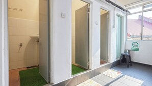 A restroom with a shower, a toilet, and a sink. There is a green mat on the floor and a sign indicating a smoking area.