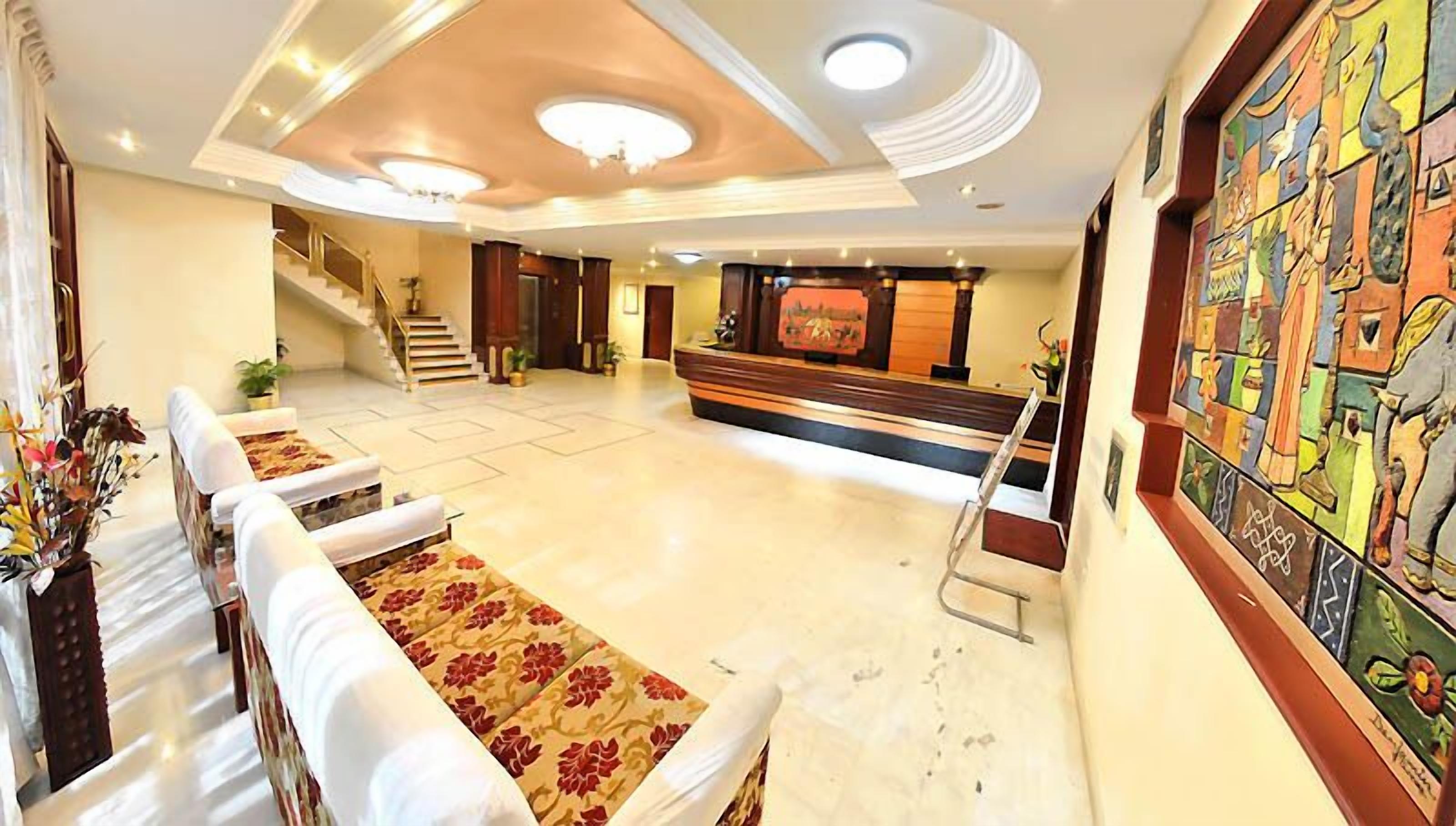 A spacious lobby with a reception desk, a staircase, and a mural on the wall.