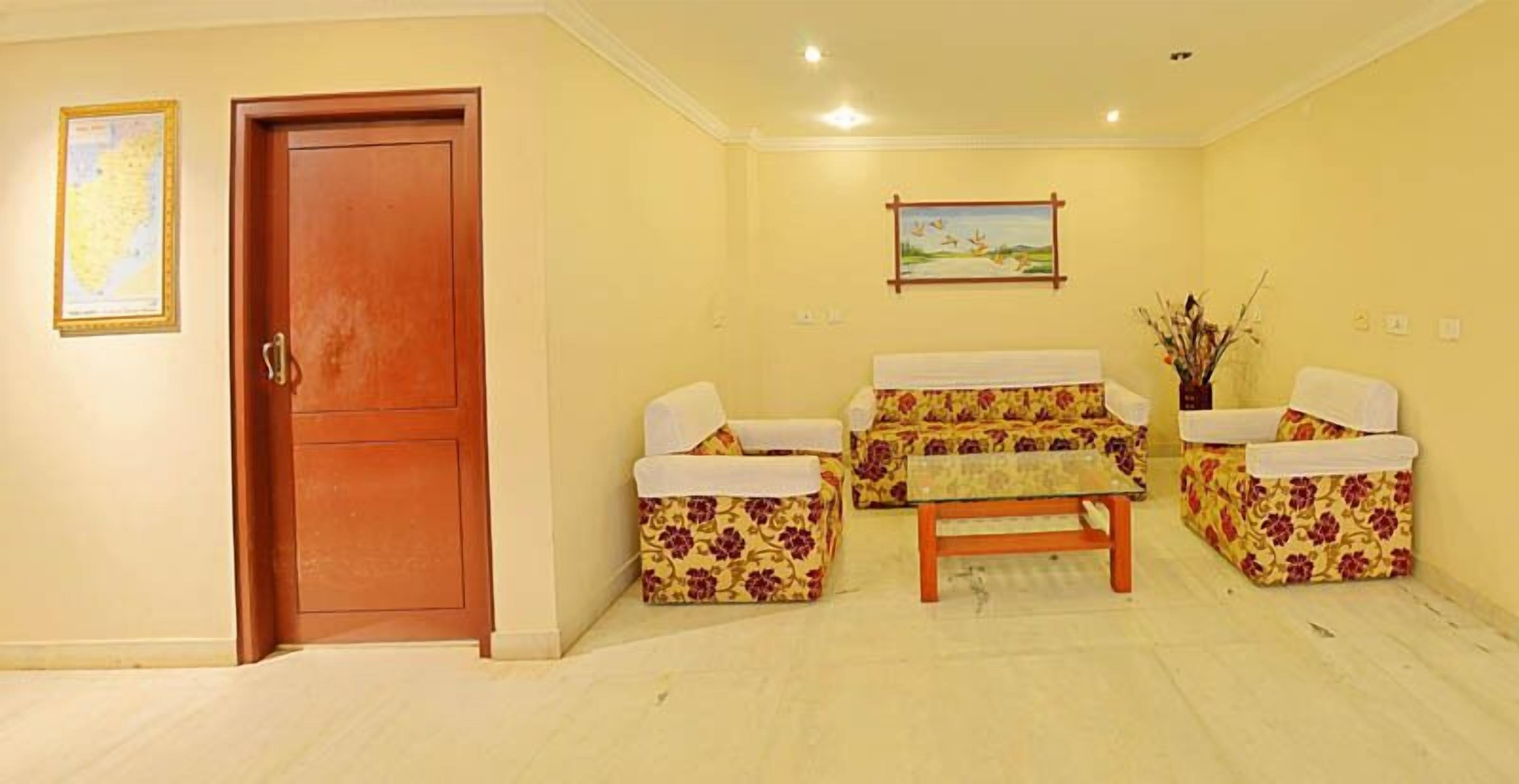 A living room with a wooden door, a sofa set, a coffee table, and a painting on the wall.