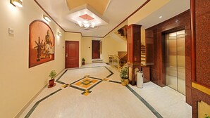 Un'elegante hall d'hotel con pavimento in marmo, una scala e un grande quadro appeso al muro.