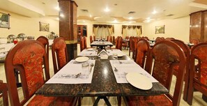 A dining area with a long table set for multiple guests, surrounded by upholstered chairs.