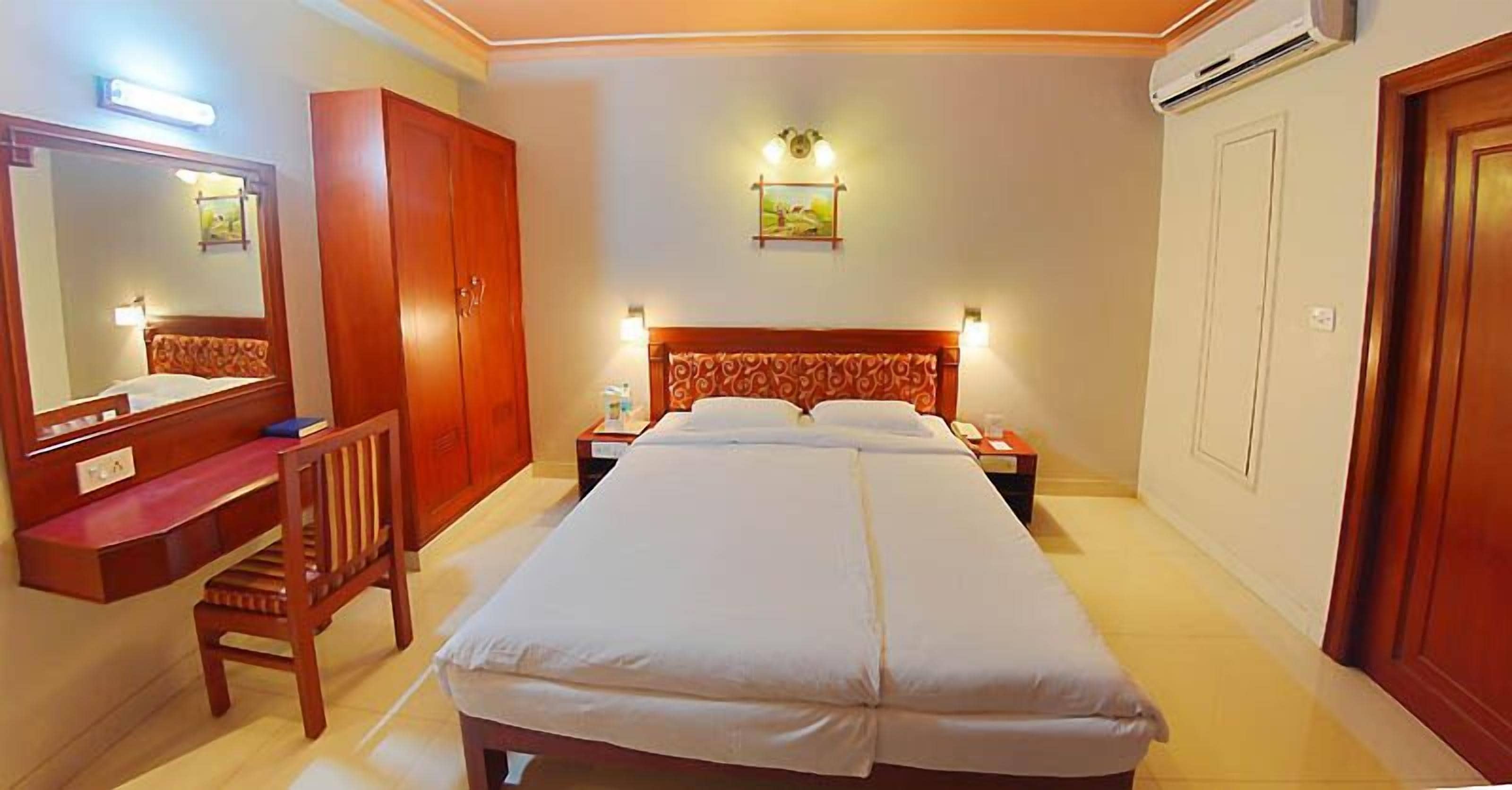 Une chambre d’hôtel avec un lit, un bureau, une chaise, une armoire et une porte de salle de bain.