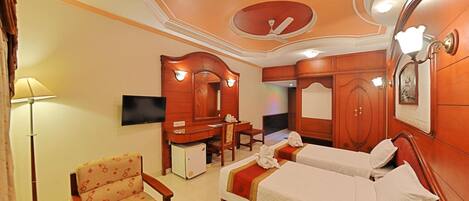 A hotel room with two beds, a desk, a chair, a TV, and a wardrobe.