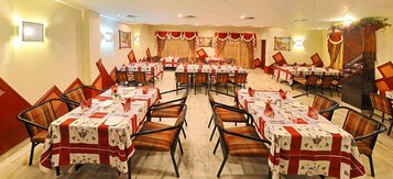 Un comedor de hotel con varias mesas dispuestas para comer, organizadas en filas con sillas.