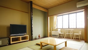Habitació japonesa tradicional amb tatami, televisió, taula i finestra amb cortines.