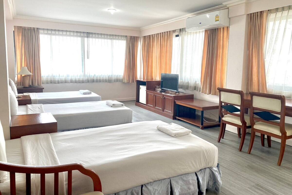 Habitación de hotel con dos camas, un escritorio, una televisión y una silla.