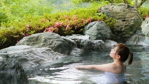 Una persona en un entorno natural, con rocas grandes y abundante vegetación.