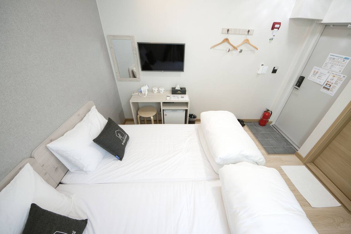 Habitación de hotel con cama, escritorio, silla, televisor y extintor.