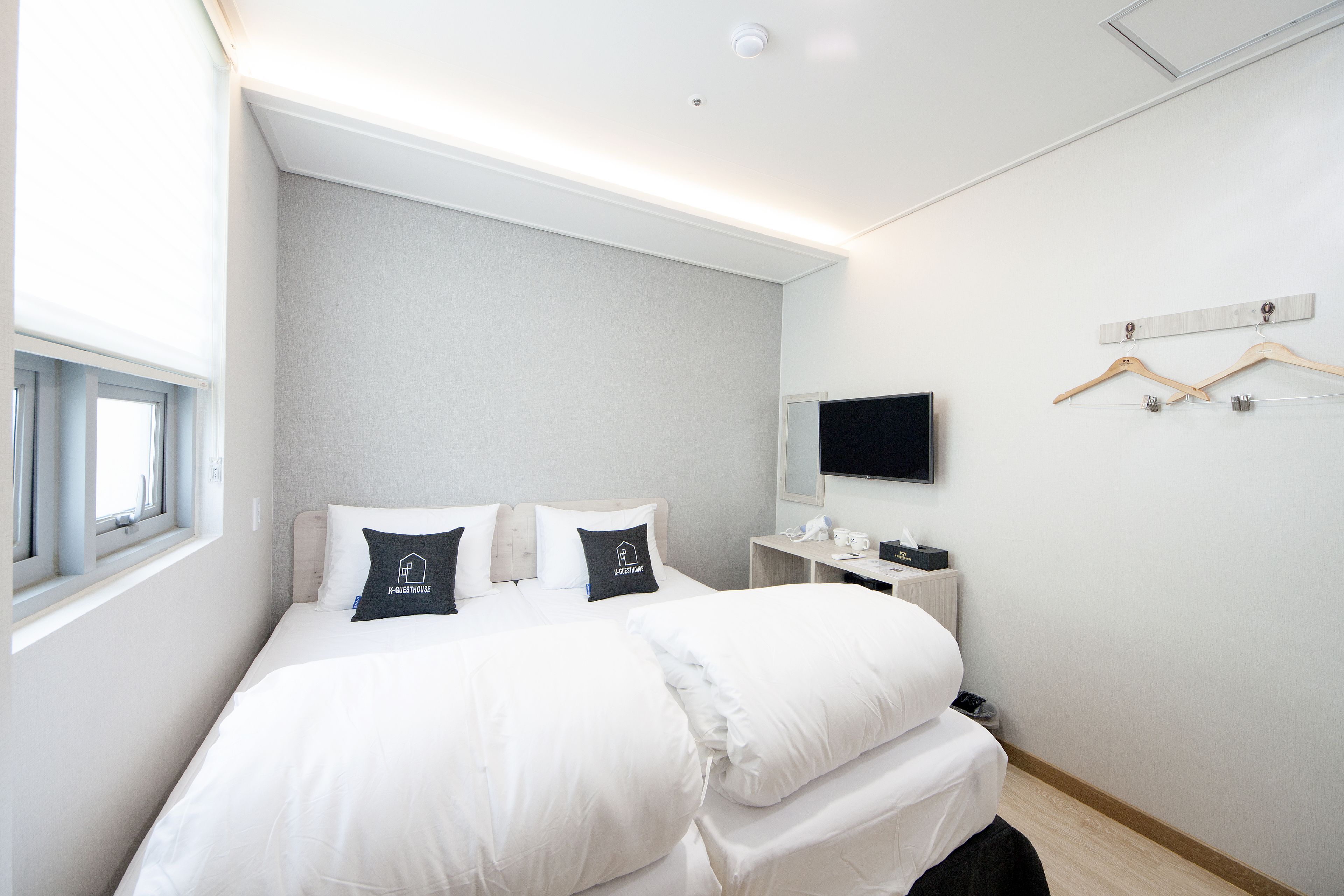 Una habitación de hotel moderna con una cama grande, un televisor de pantalla plana y un ventanal con persianas.