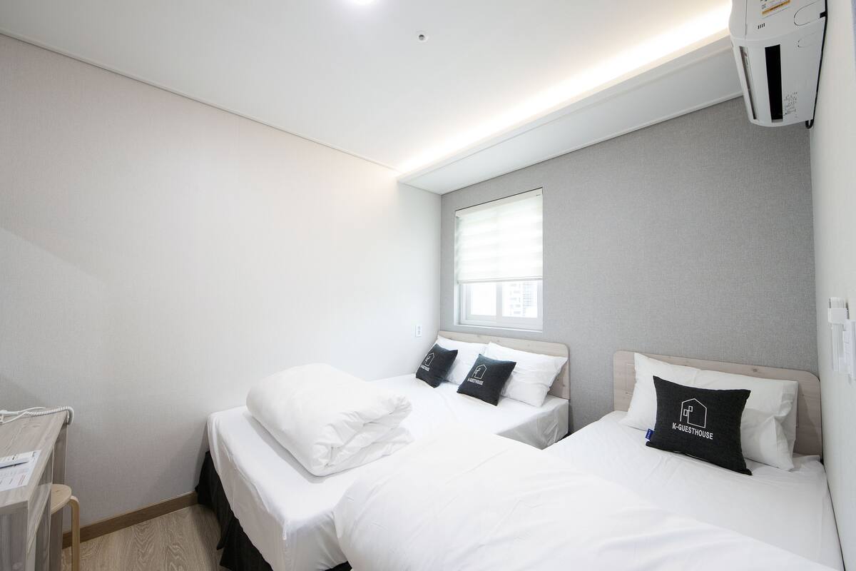Una habitación de hotel con dos camas, un escritorio y una ventana.