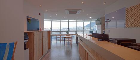 A modern kitchen with wooden cabinets, a long counter, and a large window offering a city view.