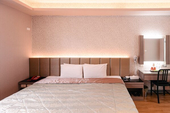 A hotel room with a bed, bedside table, desk, chair, and a mirror. - Cantaloupe Motel (Taoyuan City)