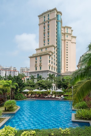 A hotel with a large swimming pool surrounded by lush greenery and palm trees.