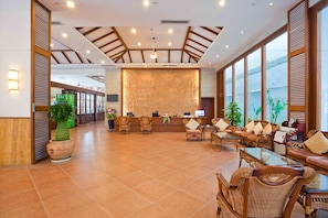 A spacious lobby with a reception desk, comfortable seating, and large windows.