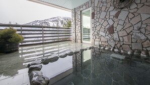 A stone-walled indoor area with a glass barrier overlooking a snowy mountain. - Rosen Heim HAKUBA (Hakuba)