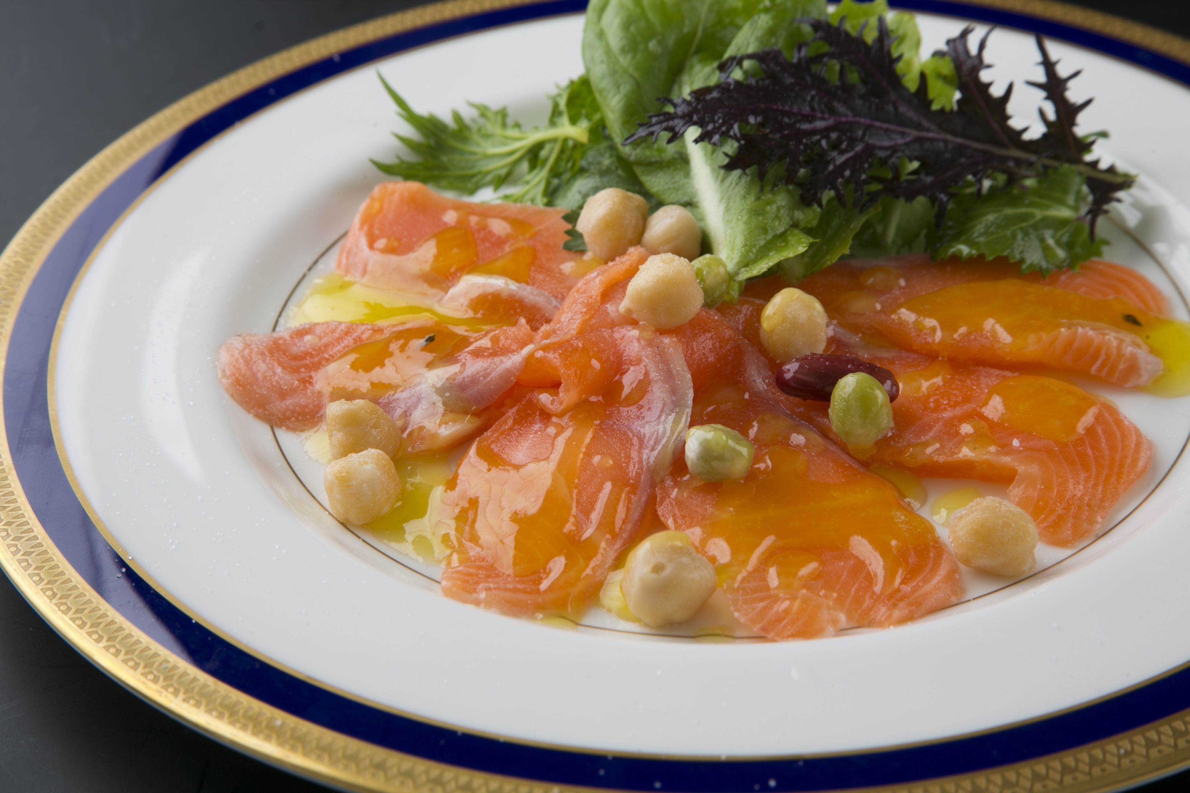 A plate of food with salmon, chickpeas, and greens.