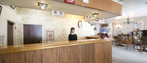 A reception desk with a wooden counter, a clock, and signs indicating 'Front' and 'Cashier' areas.
