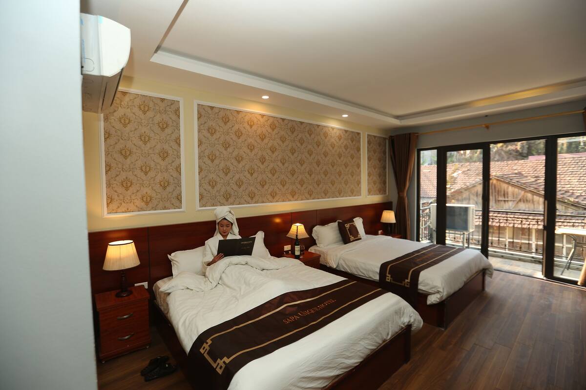 Ein Hotelzimmer mit zwei Betten, einem großen Fenster und einem Balkon.