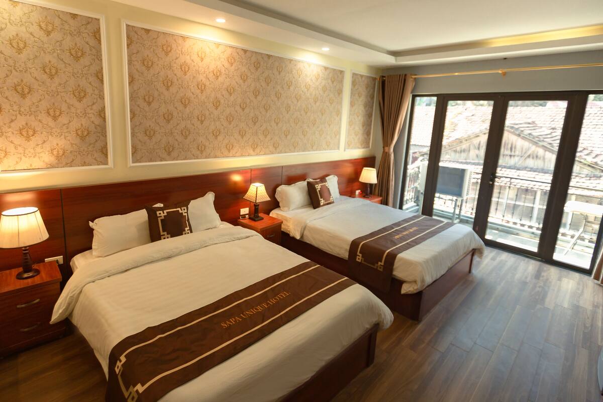 Ein Hotelzimmer mit zwei Betten, einem großen Fenster mit Blick und einer Wand mit Muster.
