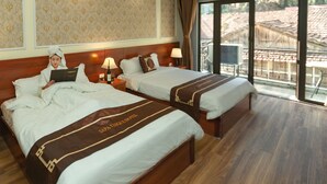 Une chambre d’hôtel avec deux lits, une grande fenêtre donnant sur un beau paysage et un papier peint à motifs.