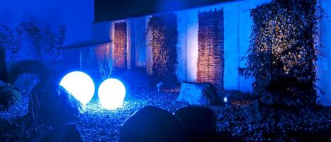 A building with a modern design, featuring a large illuminated sphere and a wall covered in climbing plants.