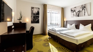 A hotel room with a bed, a desk, a television, and artwork on the walls.