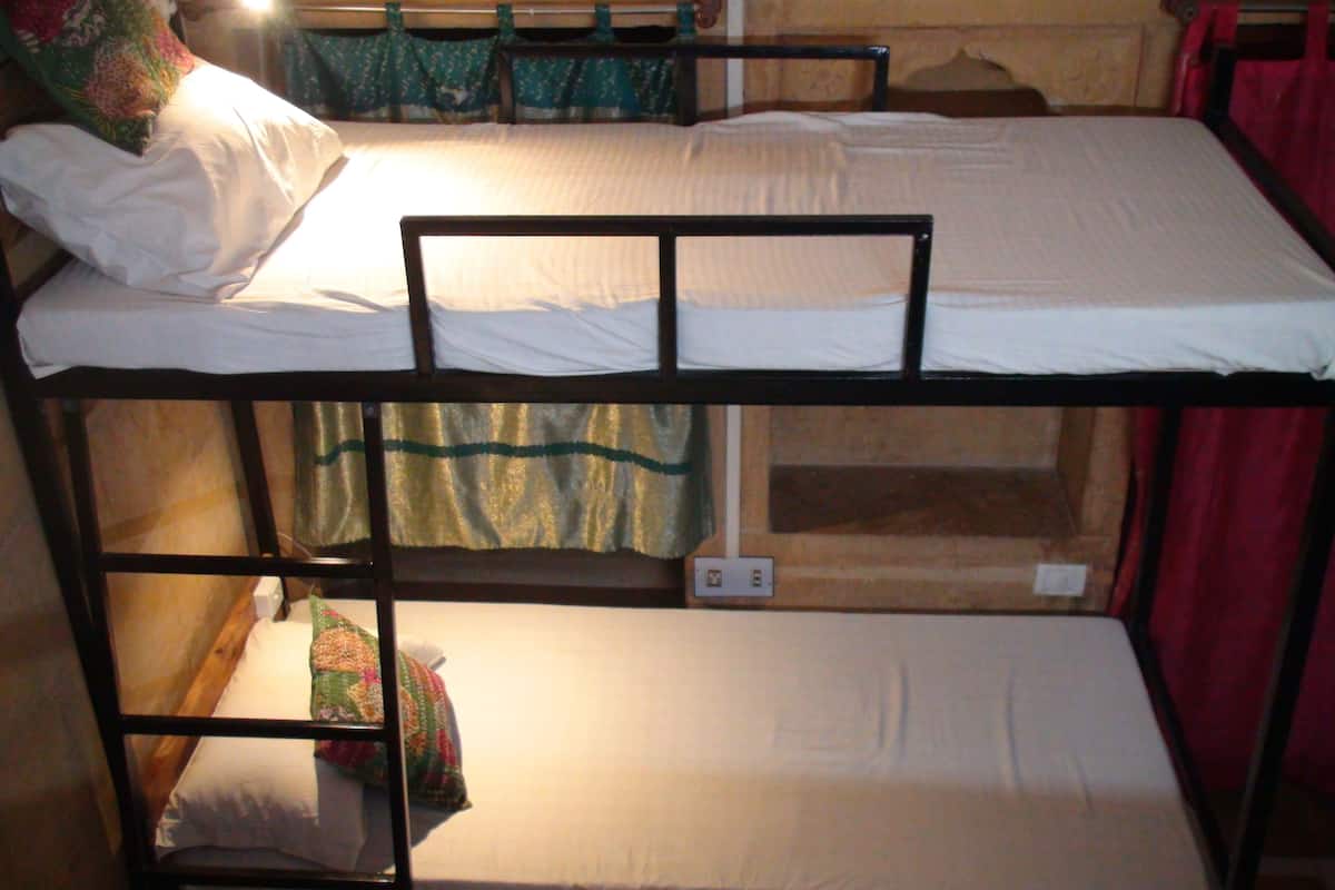 A bunk bed with two levels, each with a pillow and a blanket.