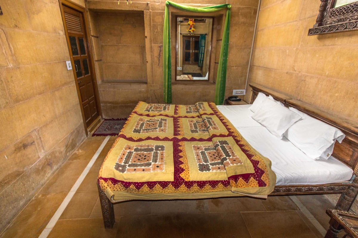 A traditional room with a bed, a wooden door, and a mirror on the wall.
