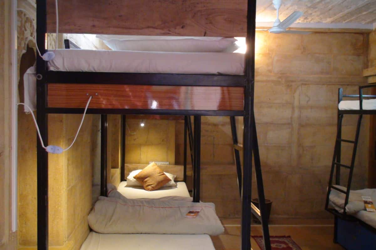 A bunk bed with a mattress and pillows, a ladder, and a small table with a book.
