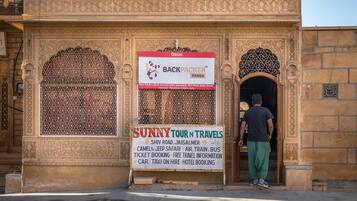A building with intricate architectural details and a signboard advertising Sunny Tour n Travels services.