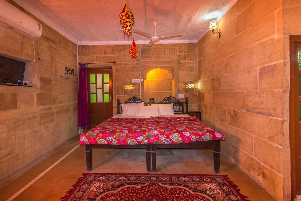 A traditional room with a bed, a ceiling fan, and a decorative hanging light fixture.